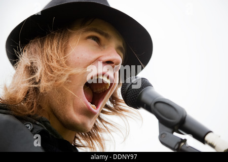 Young man in hat chante pour microphone Banque D'Images