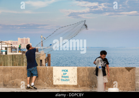 Fils de l'homme et la pêche à la crevette en jetant des éperviers de le port pour petits bateaux de Biloxi, Mississippi Banque D'Images