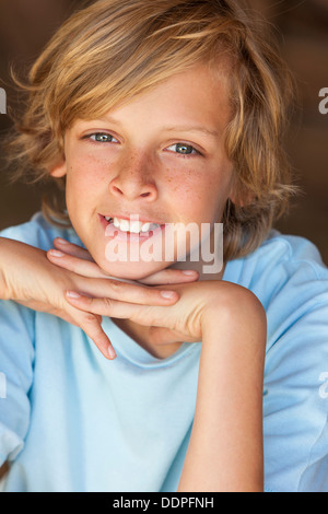 Young happy smiling blonde garçon enfant âgé d'environ douze ou au début de l'adolescence en appui sur ses mains Banque D'Images