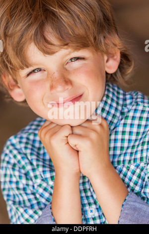 Young happy smiling blonde boy child wearing plaid shirt reposant sur ses mains Banque D'Images