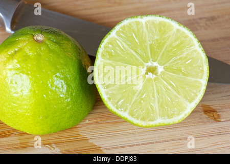 Couper le citron vert à l'aide d'un couteau sur une planche à découper Banque D'Images