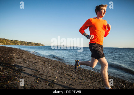 Un jeune homme qui court sur une plage de Discovery Park, Seattle, Washington, USA. Banque D'Images