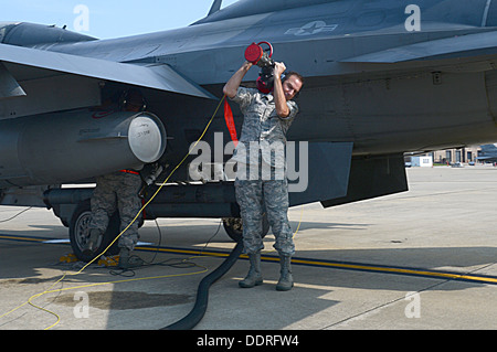 Le levage d'un tuyau de carburant sur son épaule, l'US Air Force Le Colonel Scott Arcuri, 20e Groupe de soutien de mission, commandant de l'aide dans le bain d'un ravitaillement en carburant fosses F-16 Fighting Falcon chez Shaw Air Force Base, S.C., le 28 août 2013. Sex stands ravitaillement en vol est un processus utilisé Banque D'Images