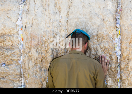 Soldat israélien prie au Mur occidental (Mur des lamentations) à Jérusalem, Israël prières sur morceaux de papier sont farcies entre les pierres Banque D'Images