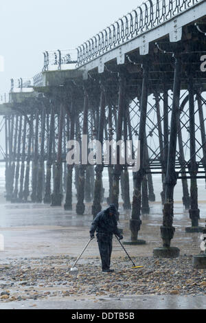 Détection des métaux l'homme sous la pluie avec détecteur de métal sur plage. UK Banque D'Images