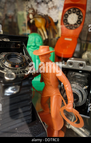 Un jouet platic cowboy, un vieil appareil photo, vintage, un vieux téléphone orange et un cheval jouet dans la fenêtre d'une boutique d'antiquités de Pittsburgh Banque D'Images