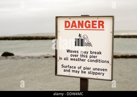 Inscription visiteurs avertissement que les ondes peuvent s'abattre sur cette jetée dans toutes les conditions météorologiques. Jetée de surface inégale et peut être glissant Banque D'Images