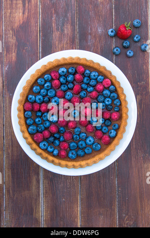 Un gâteau garni de fruits d'été - les framboises et les bleuets sur table en bois Banque D'Images