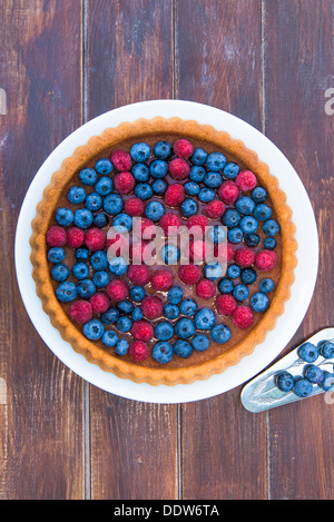 Un gâteau garni de fruits d'été - les framboises et les bleuets sur table en bois Banque D'Images