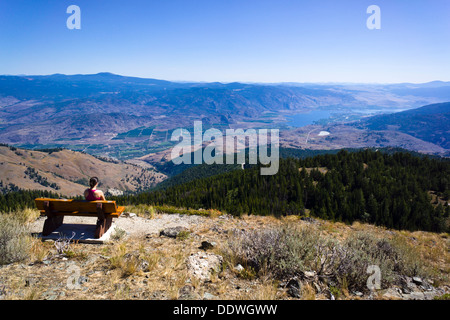 Fille sur le banc bénéficiant de vue sur la vallée de l'Okanagan sud du mont Kobau sommet. South Okanagan Grasslands, C.-B., Can. Banque D'Images