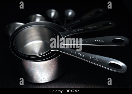 Un jeu de cuisine tasses à mesurer et cuillères photographié sur un fond noir. Banque D'Images