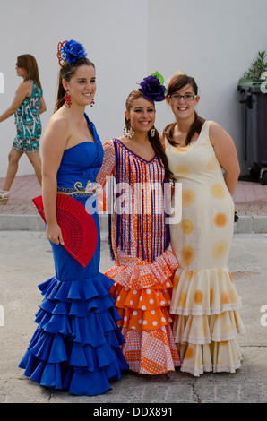 Trois jeunes filles dans un robes de flamenco traditionnel au cours de la feria annuelle à Mijas, dans le sud de l'Espagne. Costa del Sol. Banque D'Images