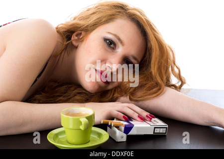 Jeune femme avec cheveux rouges, se détendre avec UN café espresso et des cigarettes fort le matin, isolé sur blanc Banque D'Images