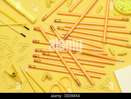 Fournitures scolaires jaune. Des crayons, des gommes, des trombones, des brosses, des épingles, des ciseaux, du papier portant de manière aléatoire Banque D'Images