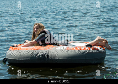 Fille couchée sur un radeau dans un lac, le lac des Bois, Keewatin (Ontario), Canada Banque D'Images