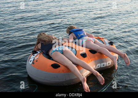 Deux jeunes filles se trouvant sur un radeau flottant sur l'eau, lac des Bois, Ontario, Canada Banque D'Images