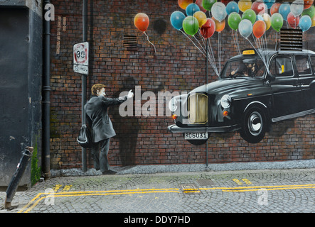 Homme mur graffiti, saluant un taxi suspendu à ballons Banque D'Images