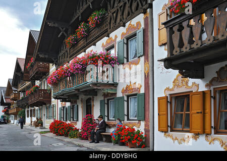 Maisons avec des peintures murales traditionnelles appelées Lueftlmalerei, balcons ornés de géraniums (Pelargonium) Banque D'Images