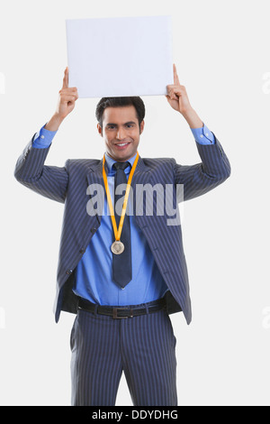 Businessman with medal holding a placard Banque D'Images