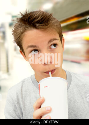 Portrait, garçon, adolescent boire d'une tasse avec une paille dans une station de métro Banque D'Images