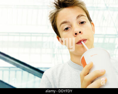 Portrait, garçon, adolescent boire d'une tasse avec une paille Banque D'Images