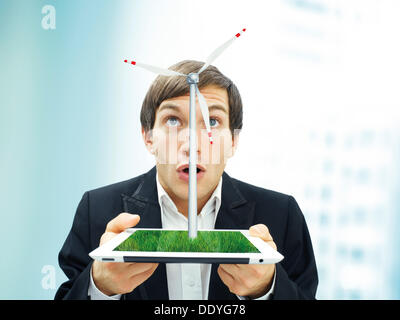 Businessman with a surpris face à la tenue d'un iPad avec une éolienne, image symbolique pour l'énergie durable Banque D'Images