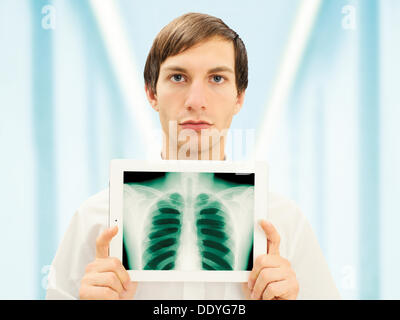 Homme avec un visage sérieux tenant un iPad avec une image radiographique d'un poumon Banque D'Images