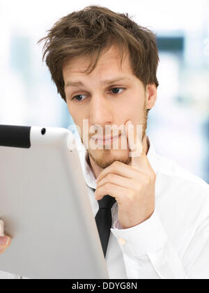 Portrait of a businessman holding un iPad, à la concentration, Sérieux, réfléchi, concerné, l'entraide, au bureau Banque D'Images