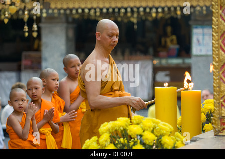 Le moine bouddhiste et moines novices debout dans une ligne parfaite au cours de la prière du soir, Wat Phra That Doi Suthep, Chiang Mai, Thaïlande Banque D'Images