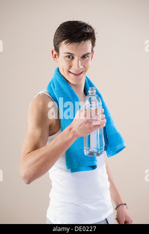 Smiling young man holding faire du sport après une bouteille d'eau dans sa main Banque D'Images