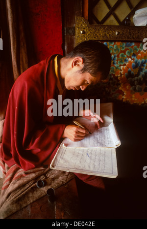 Moine Novice de la copie des textes sacrés à l'étage dans le Utse Temple, Monastère de Samye Samye, Tibet, Banque D'Images