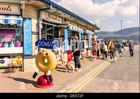 Les visiteurs de la file d'attente pour un casse-croûte à côté de la chaussée d'essence en gallois sea resort de Barmouth, sunny mountain l'arrière-plan. Banque D'Images