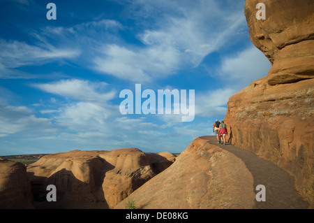 Jeune couple de touristes en randonnée sur le sentier de montagne vers Delicate Arch, Arches National Park, Utah, United States of America Banque D'Images