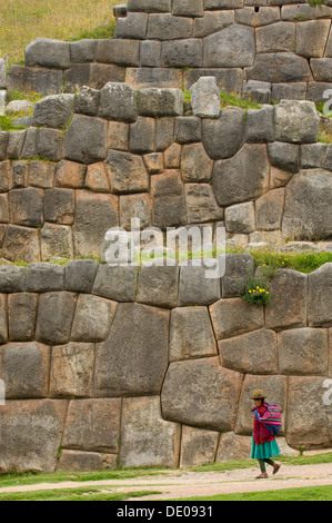 Femme en robe traditionnelle des Andes et hat, en passant devant le maintien de la paroi mitoyenne pierres imbriquées, Saksaywaman, Cusco, Pérou Banque D'Images