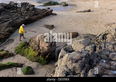 Un homme marche par l'une des plages de Finisterre, connu pour être visité par les pèlerins pour regarder le coucher du soleil. Banque D'Images