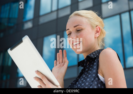 Young woman waving at digital tablet Banque D'Images