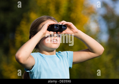 Girl looking through binoculars Banque D'Images