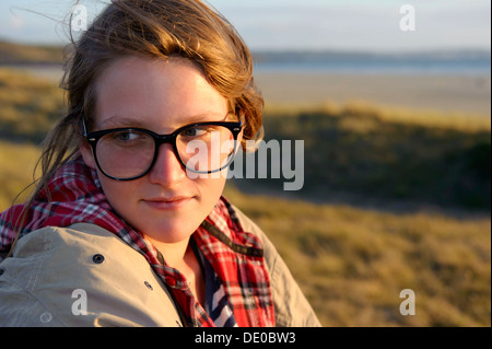 Une jeune femme avec de grandes lunettes noires assis sur une dune, Bretagne, France, Europe Banque D'Images