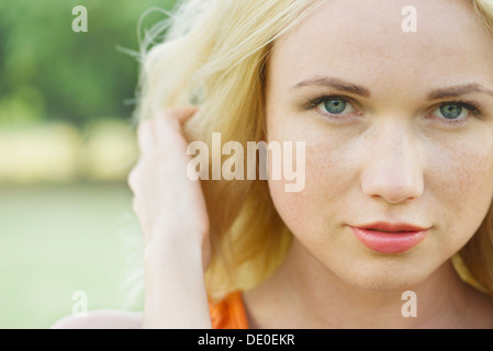 Jeune femme avec la main dans les cheveux, portrait Banque D'Images