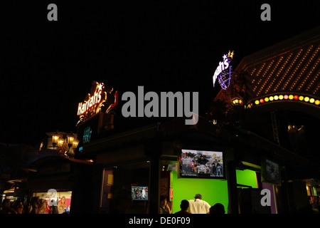 Vue de nuit, à façade néon Harrah's Casino, les gens qui regardent l'homme à l'écran vert 'vélo' célèbre Vegas, Las Vegas, USA Banque D'Images