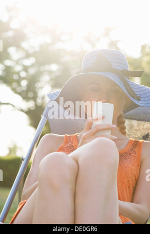 Jeune femme de détente en plein air avec smartphone Banque D'Images