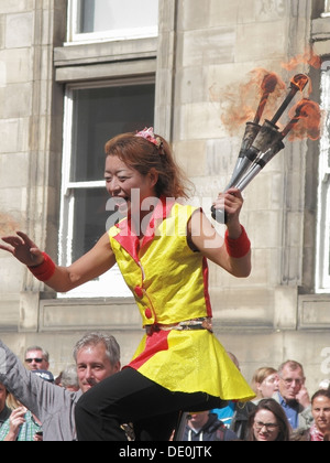 Artiste de rue chinois équitation un monocycle avec des torches enflammées, le Royal Mile, Édimbourg, Écosse, Royaume-Uni Banque D'Images