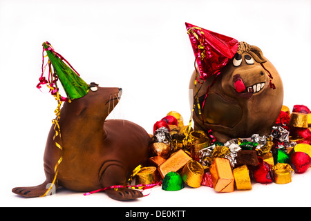 Deux animaux d'argile dans une partie. Happy Cow sur un haut chocolat, désapprouvant sea lion, debout sur un tas de bonbons et d'emballage, Banque D'Images