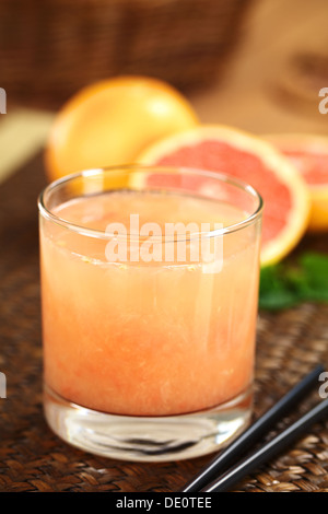 Jus de fruit frais de la rose pamplemousse à chair avec des pailles noires sur le côté et des pamplemousses dans l'arrière Banque D'Images