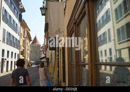 Balade dans les ruelles de Yverdon-les-Bains avec des réflexions dans une fenêtre et la tour du château de ville au bout de l'allée Banque D'Images