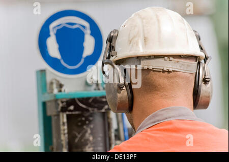 Signe de protection de l'ouïe, l'homme portant un casque avec la protection contre le bruit sur une ligne de galvanisation, Salzgitter AG Steel Mill, Salzgitter Banque D'Images