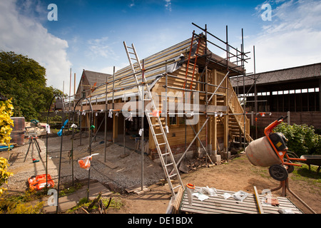 L bâtiment maison, la construction en bois de chêne vert, garage structure externe autour d'échafaudages Banque D'Images