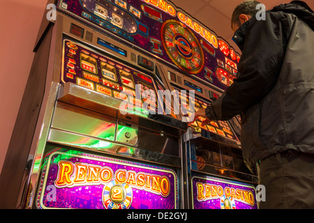 L'homme jouant sur des machines à sous. Banque D'Images