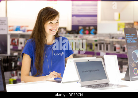 Spécialiste Google femelle dans les boutiques informatiques démontrant un ordinateur portable de Google Chromebook Banque D'Images