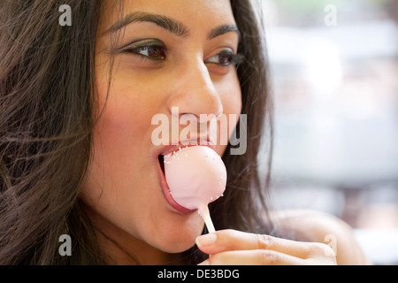 Woman eating a cake pop Banque D'Images